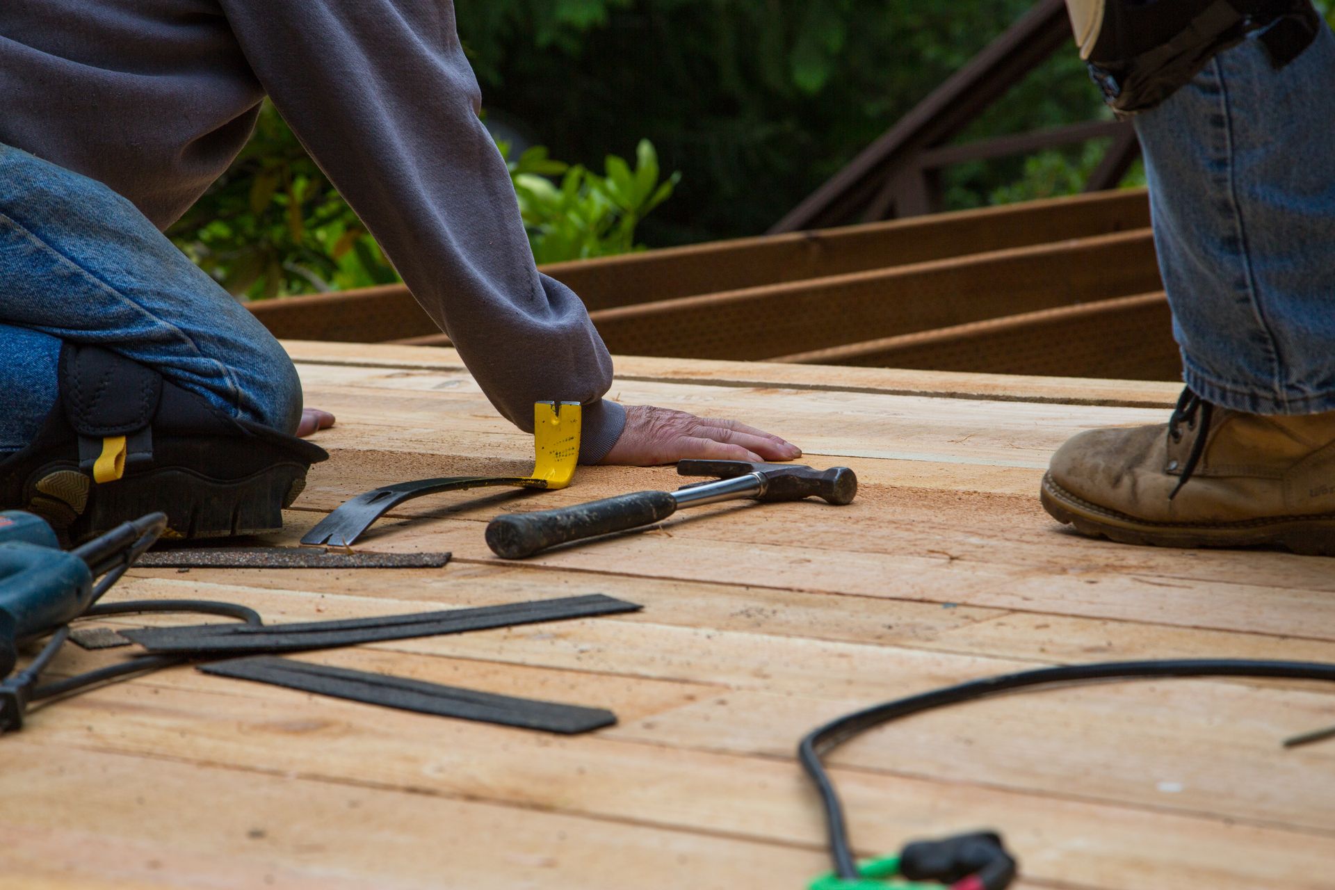 two workers doing deck repair with tools 