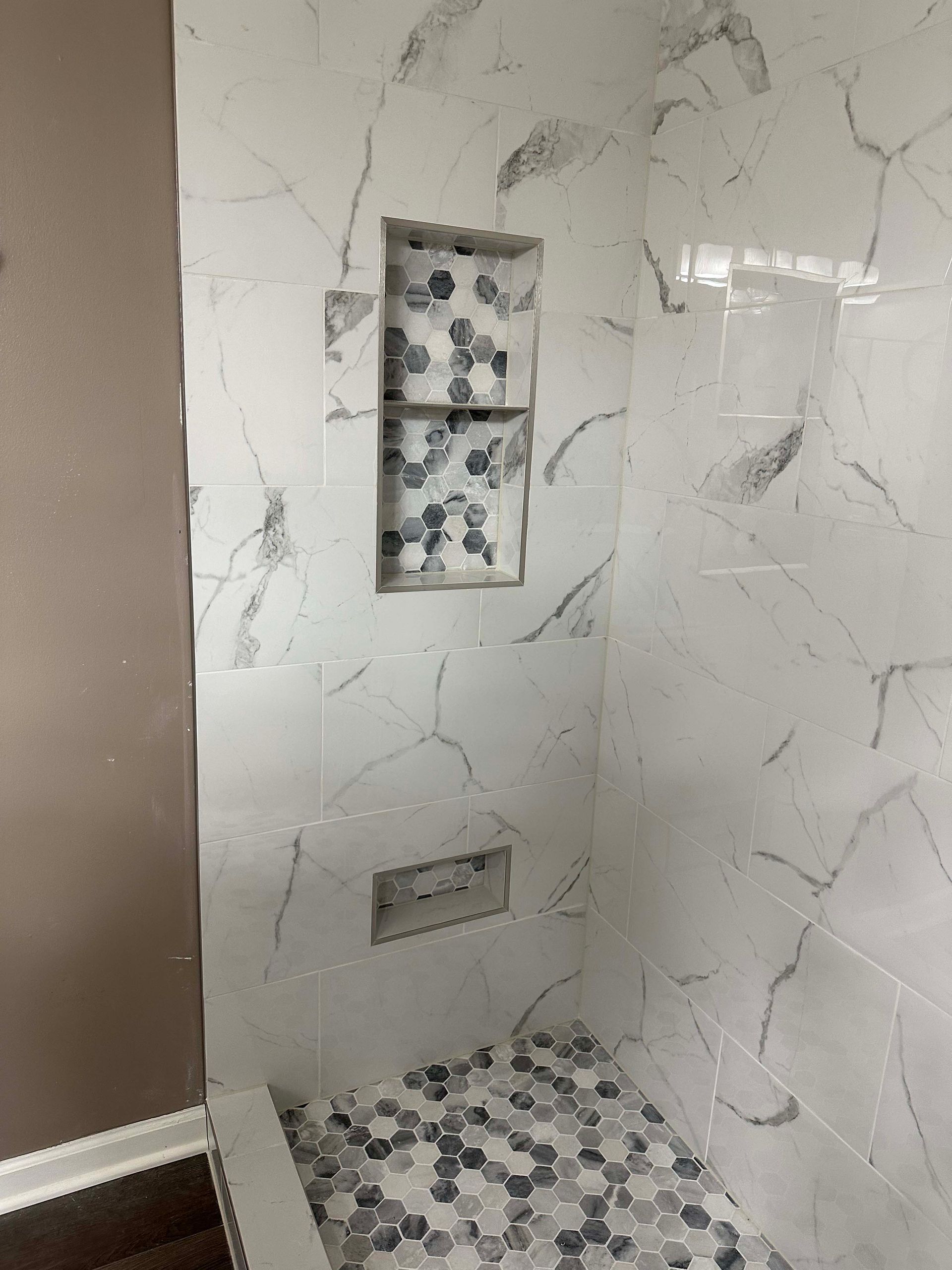 A bathroom with marble tiles and a walk in shower.