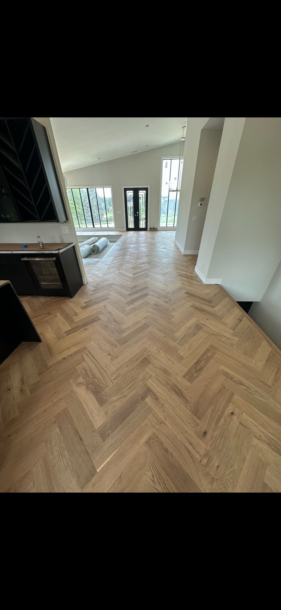 A living room with a wooden floor and a herringbone pattern.