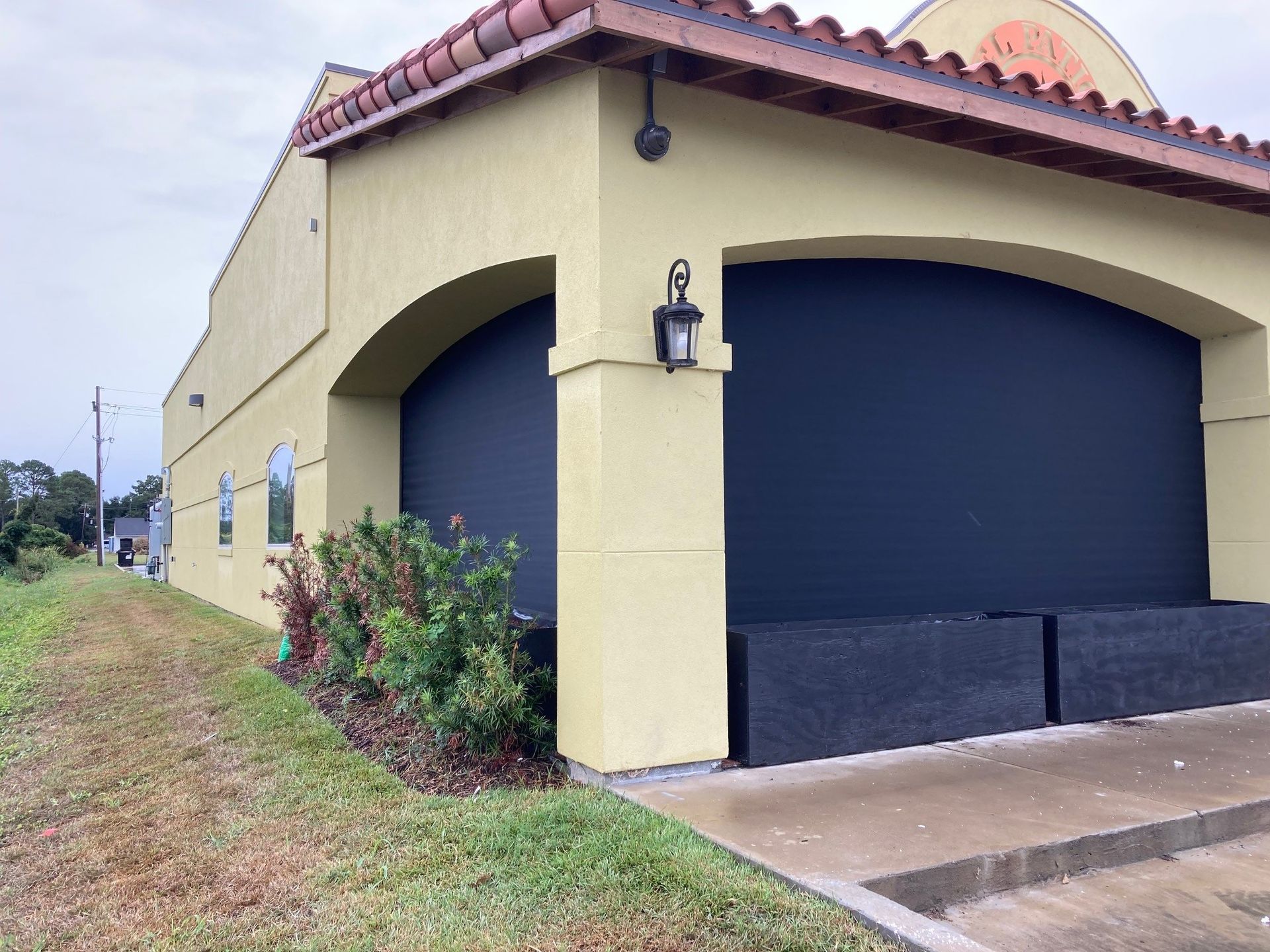 A yellow building with a black door and a lantern on the side.