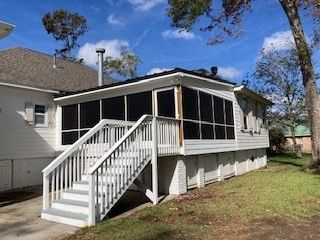 A white house with a screened in porch and stairs.