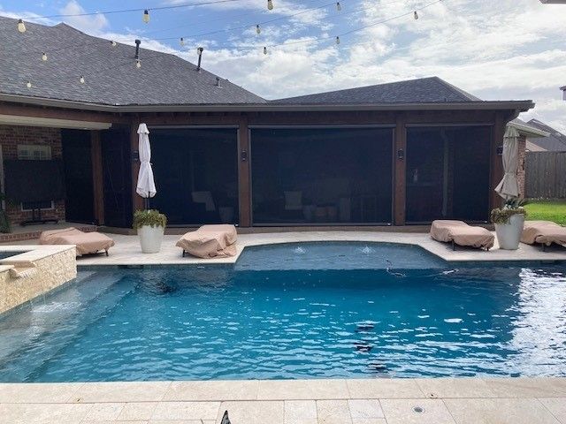 There is a large swimming pool in the backyard of a house.