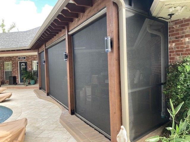 A brick house with a screened in porch and a swimming pool.