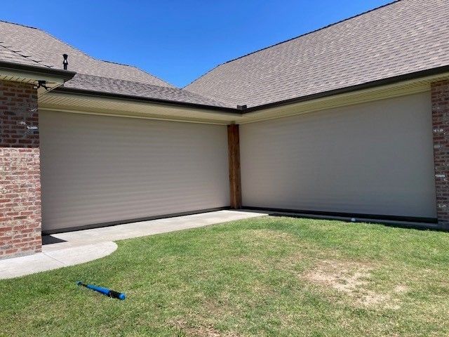 There is a baseball bat in the grass in front of a house.