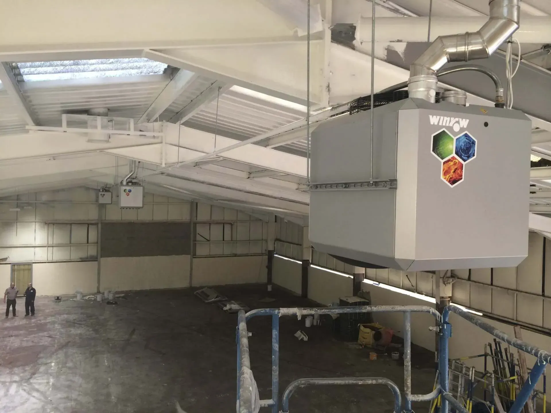 3 large warm air heating system with the word winch on it is hanging from the ceiling of a building.
