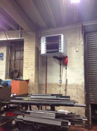 a warehouse with a lot of pipes and a warm air heater on the wall .