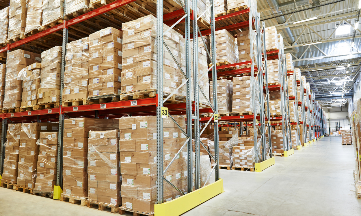 Warehouse aisle with stacked cardboard boxes on tall red-and-white shelving