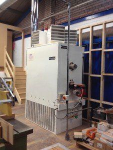 a large white water heater is sitting in a room next to a staircase .