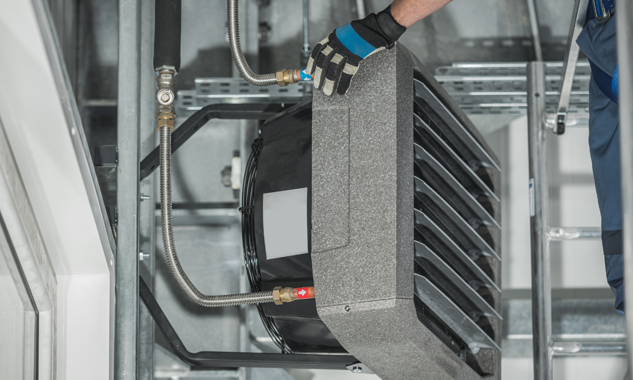 Gloved hand holding a black vent filter inside a glass-paneled industrial machine