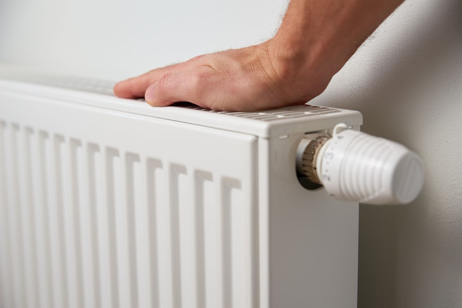 A person is touching a radiator with their hand.