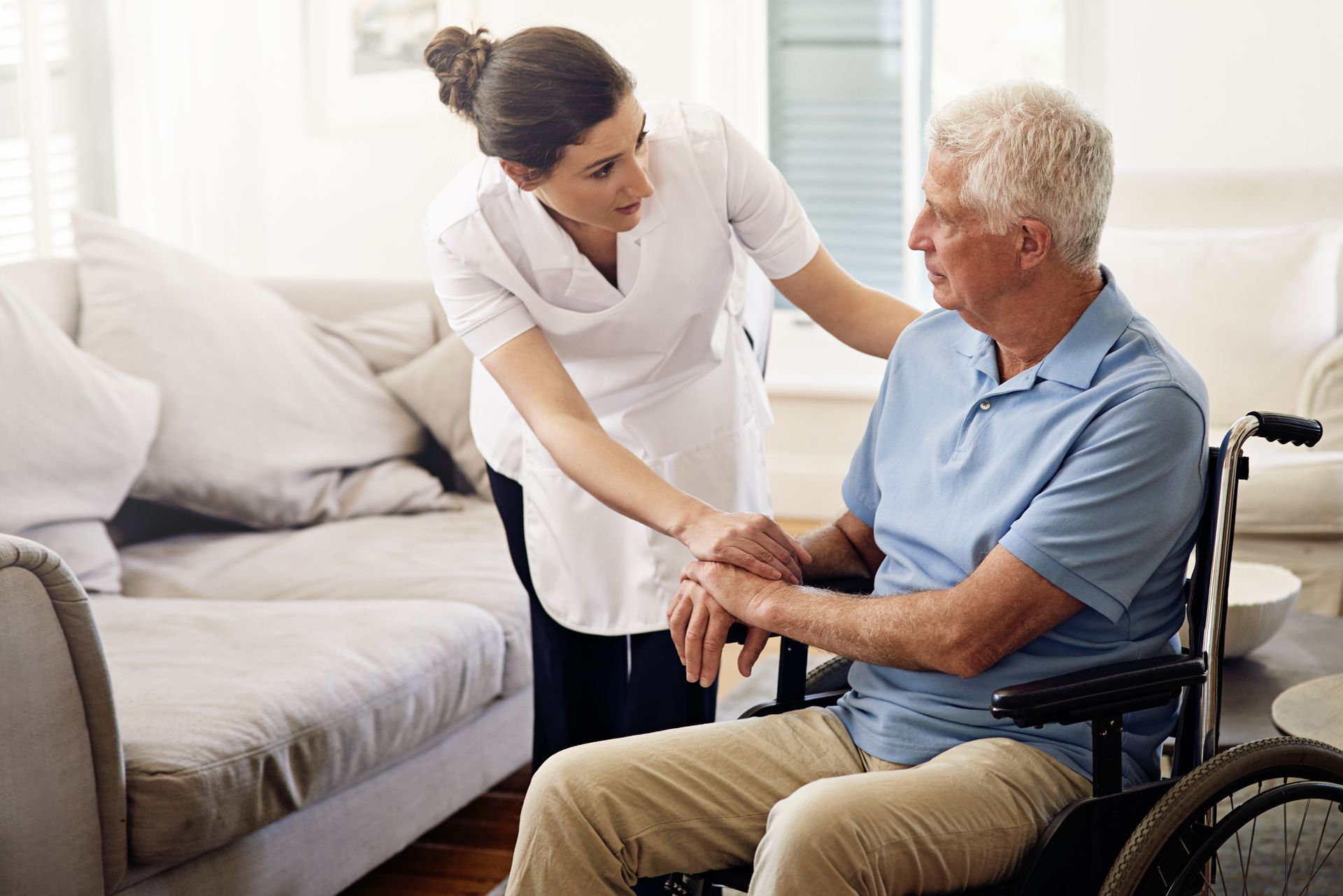 A nurse is helping an elderly man in a wheelchair.