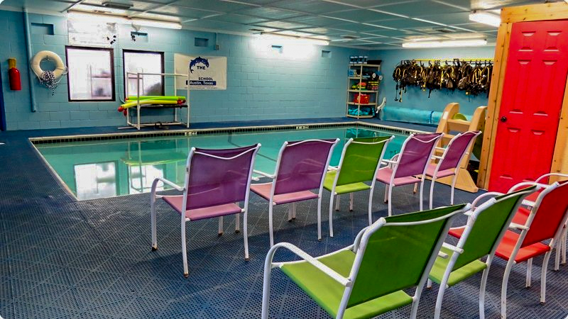 Indoor swimming pool with colorful chairs for observation.