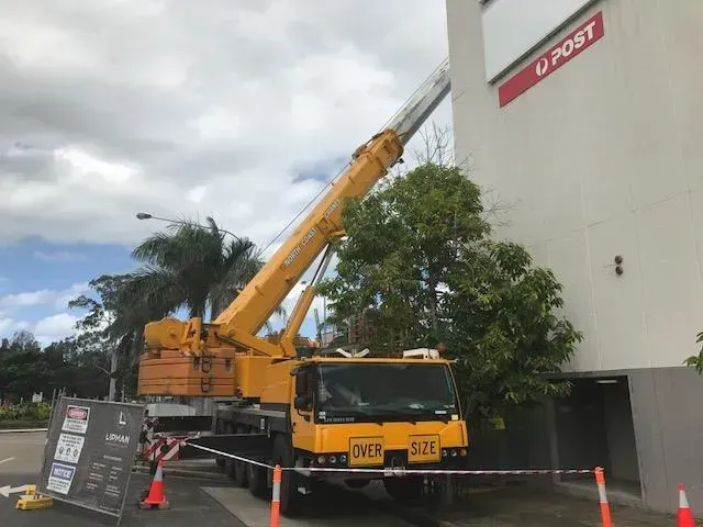 A Large Yellow Crane Is Parked in Front of A Building that Says U Post — North Coast Cranes In Coffs Harbour, NSW