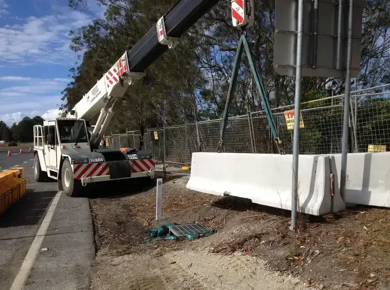 A Crane Is Lifting a Concrete Barrier on The Side of The Road — North Coast Cranes In Coffs Harbour, NSW