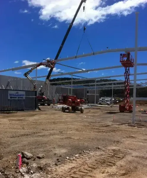 A Crane Is Lifting a Metal Structure in A Construction Site — North Coast Cranes In Coffs Harbour, NSW