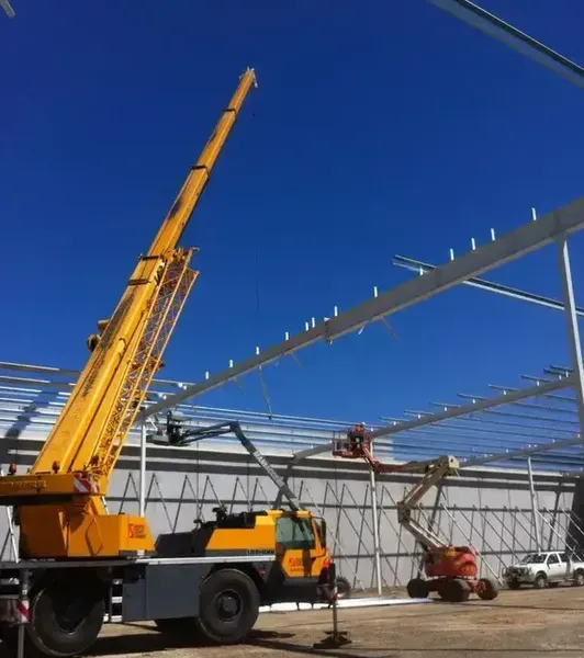 A Large Yellow Crane Is Sitting in Front of A Building Under Construction — North Coast Cranes In Coffs Harbour, NSW