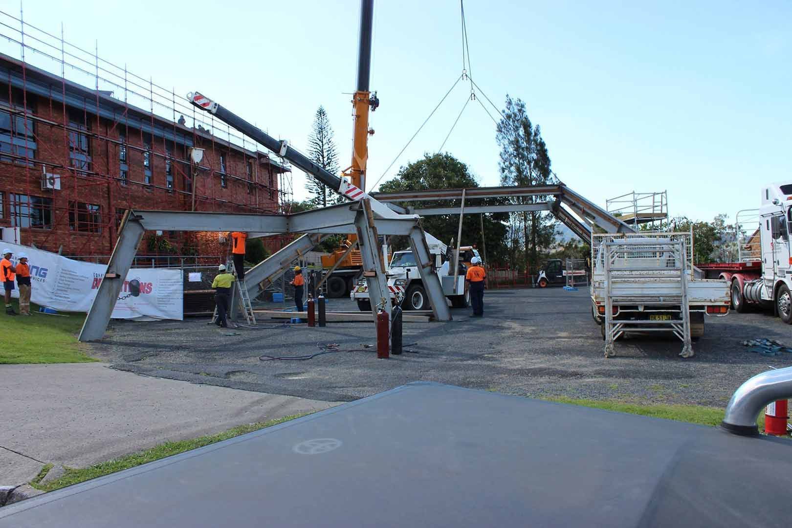 A Crane Is Lifting A Metal Structure In A Parking Lot — North Coast Cane in Woolgoolga, NSW