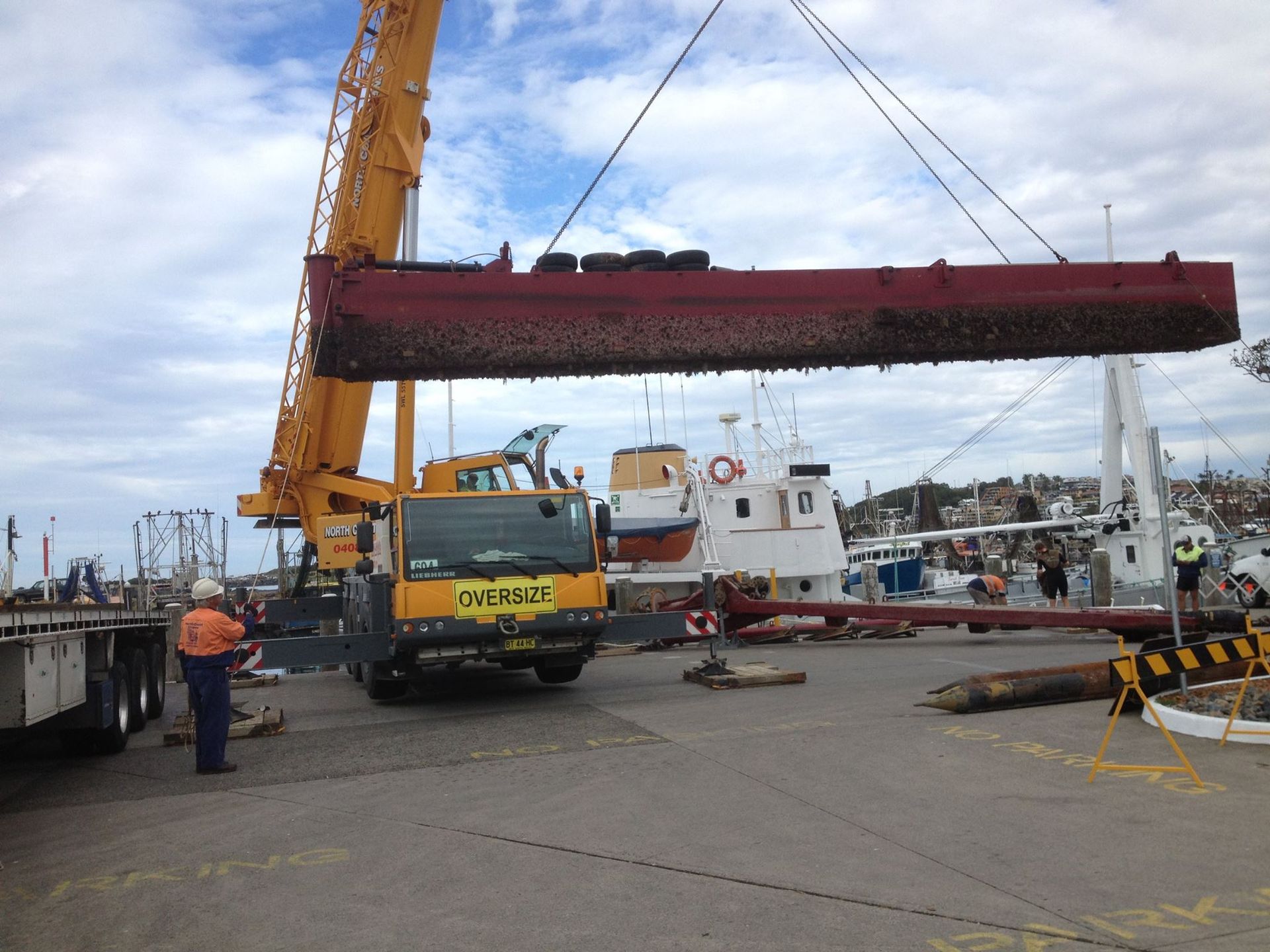 A Crane Is Lifting A Large Piece Of Metal In A Harbor — North Coast Cranes In Bellingen, NSW