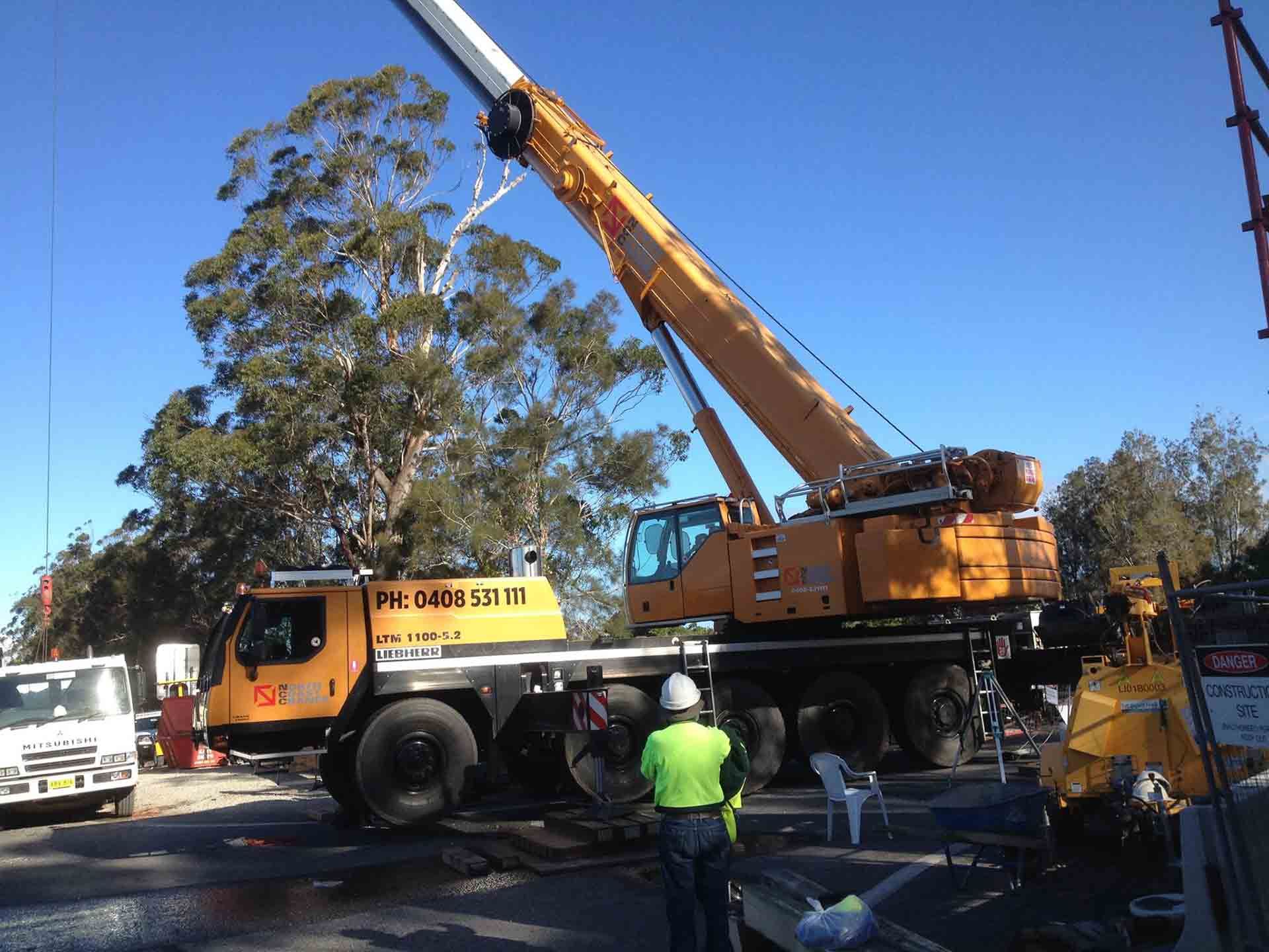 A Large Yellow Crane Is Parked In A Parking Lot — North Coast Cranes In Armidale, NSW
