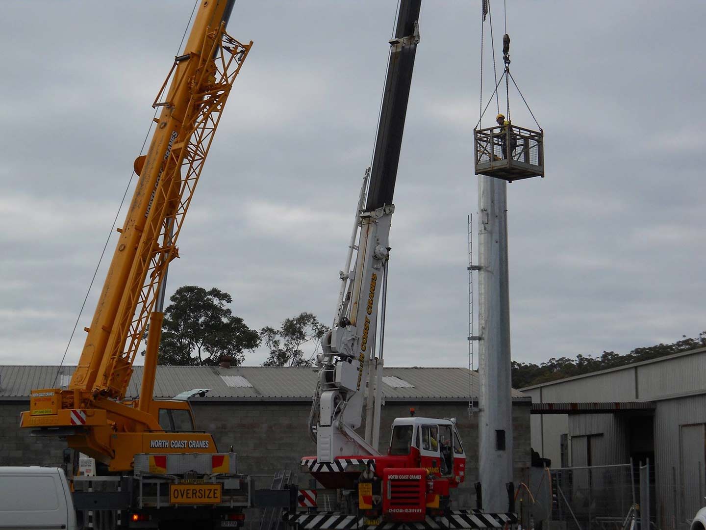 A Crane Is Lifting A Pole In A Parking Lot — North Coast Cranes In Grafton, NSW