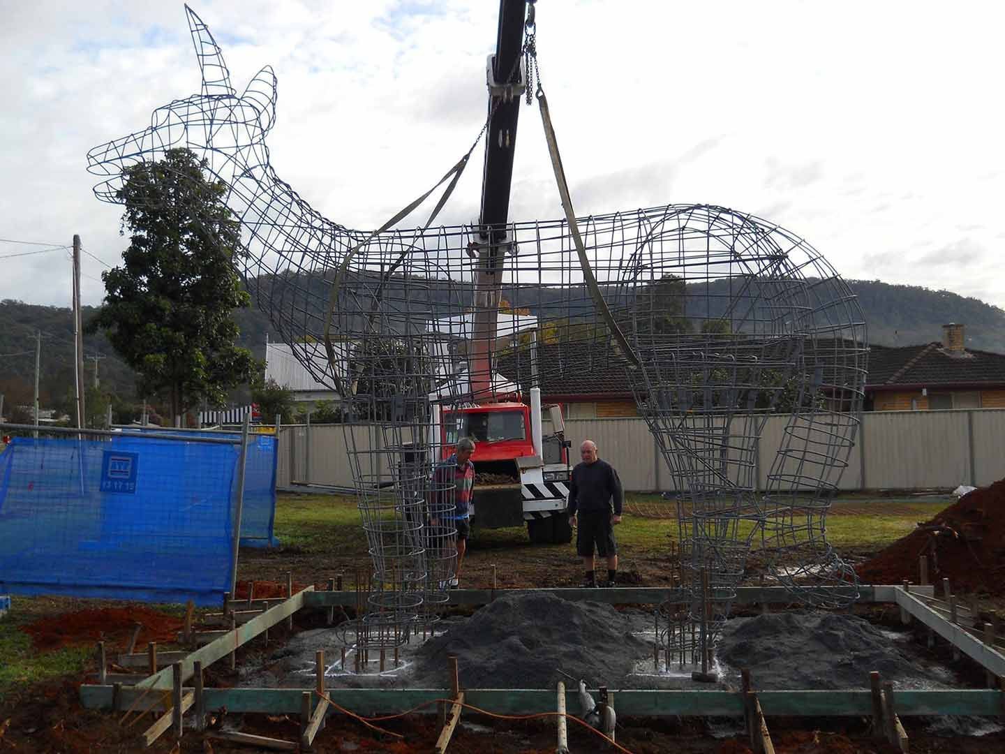 A Man Is Standing In Front Of A Large Metal Sculpture Being Lifted By A Crane — North Coast Cranes In Bellingen, NSW