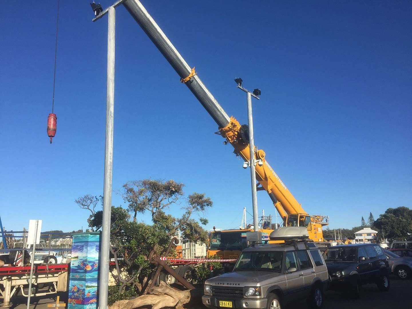 A Large Crane Is Working On A Street Light In A Parking Lot — North Coast Cranes In Grafton, NSW