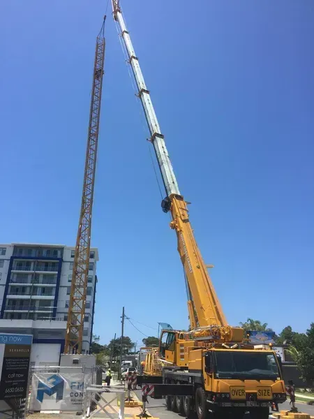 A Large Yellow Truck with A Crane Attached to It Is Parked in Front of A Building — North Coast Cranes In Coffs Harbour, NSW