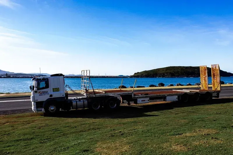 A White Truck Is Parked in A Field In Front Of A Lake — North Coast Cranes In Coffs Harbour, NSW