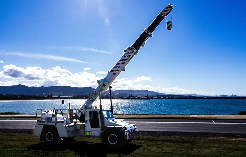 A White Truck with A Crane Attached to It Is Parked on The Side of The Road — North Coast Cranes In Coffs Harbour, NSW