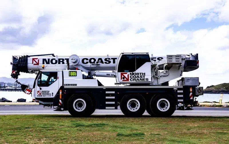 A White Truck With A Crane Is Parked In A Field — North Coast Cranes In Grafton, NSW