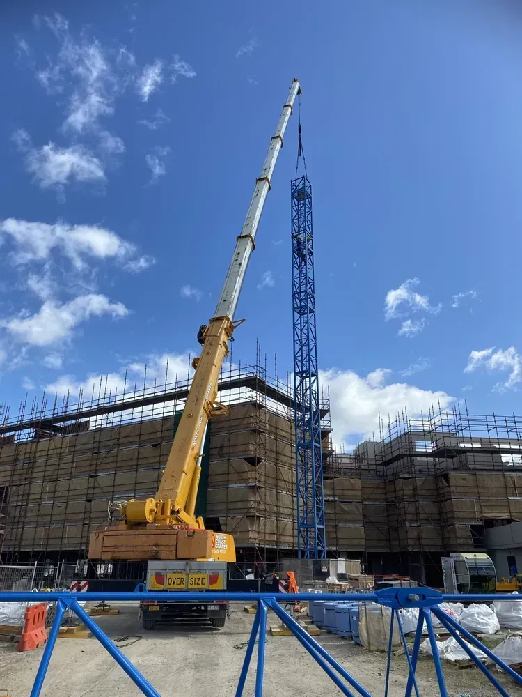 A Large Yellow Crane Is Sitting in Front of A Building Under Construction — North Coast Cranes In Grafton, NSW
