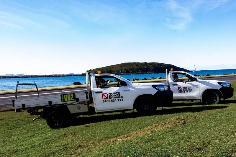 Two Trucks Are Parked Next to Each Other in A Grassy Field — North Coast Cranes In Coffs Harbour, NSW