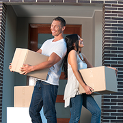 Couple standing in front of a house carrying boxes