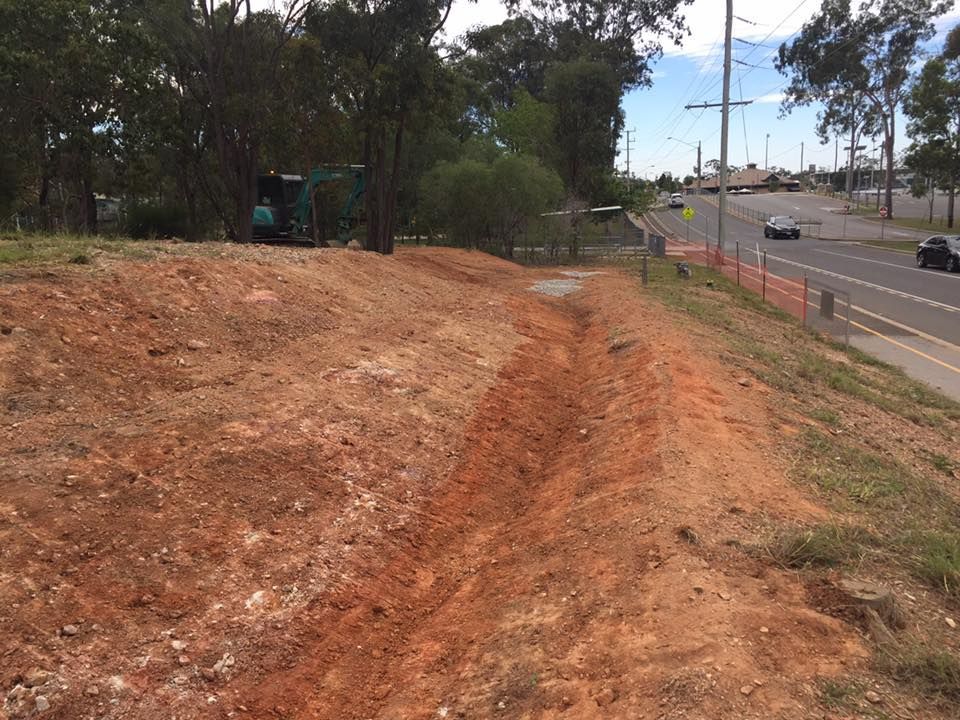 A Dirt Road Going Through a Field next to a Road — Curtis Coast Excavators in Gladstone, QLD