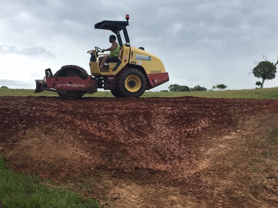 A Man is Driving a Bulldozer on a Dirt road — Curtis Coast Excavators in Gladstone, QLD