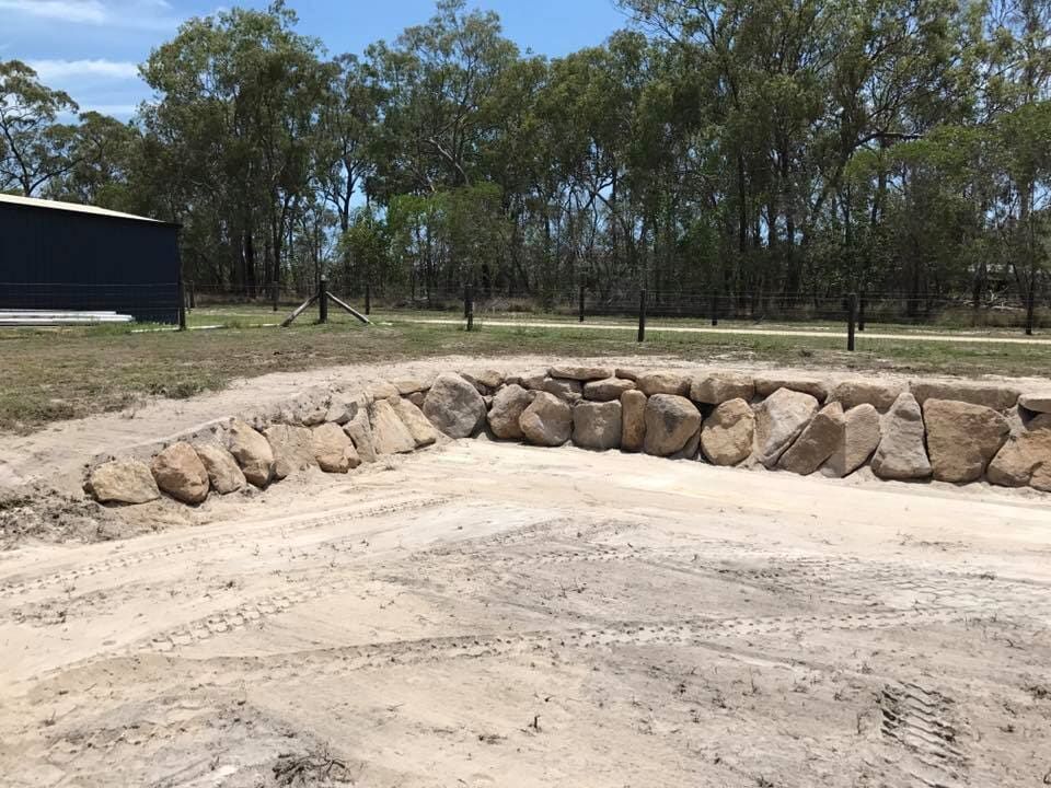 A Row of Rocks Sitting on top of a dirt field — Curtis Coast Excavators in Gladstone, QLD