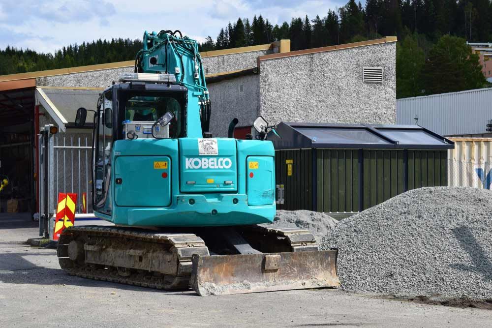 A Kobelco Excavator is Parked in Front of a Pile of Gravel — Curtis Coast Excavators in Gladstone, QLD