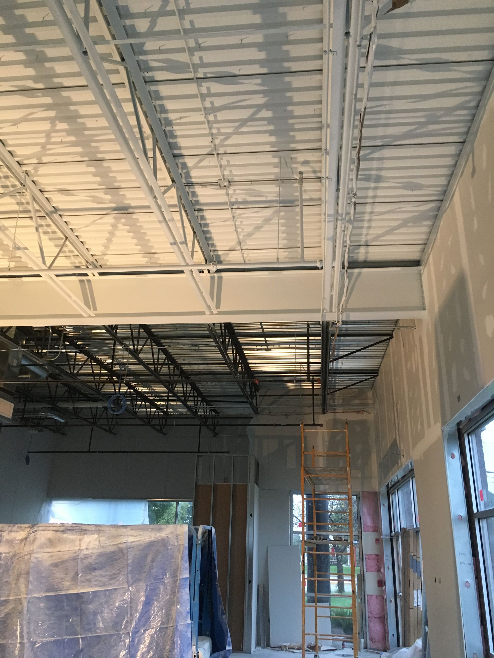 Beige ranch-style house with a brown tile roof and a two-car garage under a blue sky.