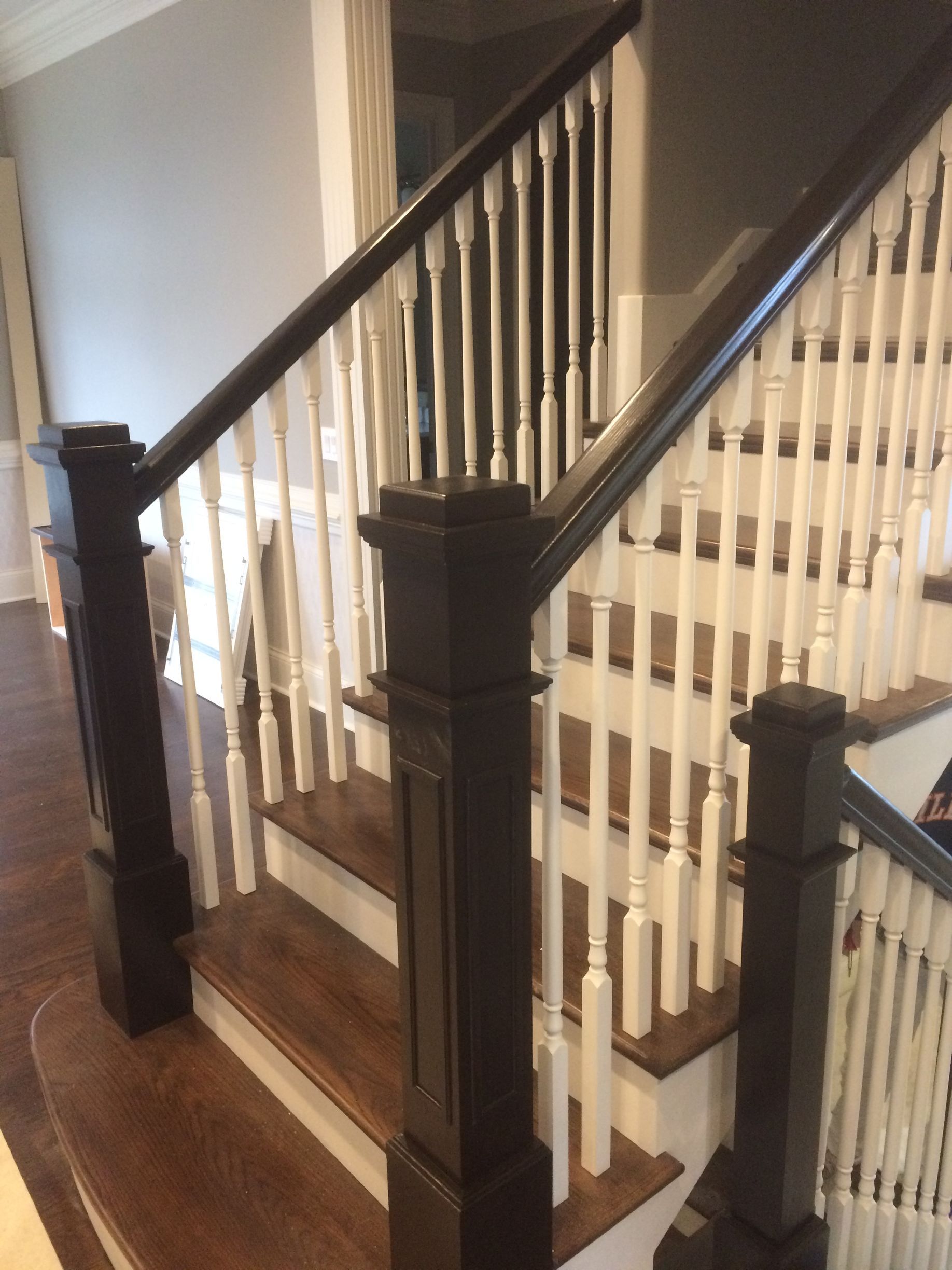 Person painting exterior window trim on a two-story beige house.