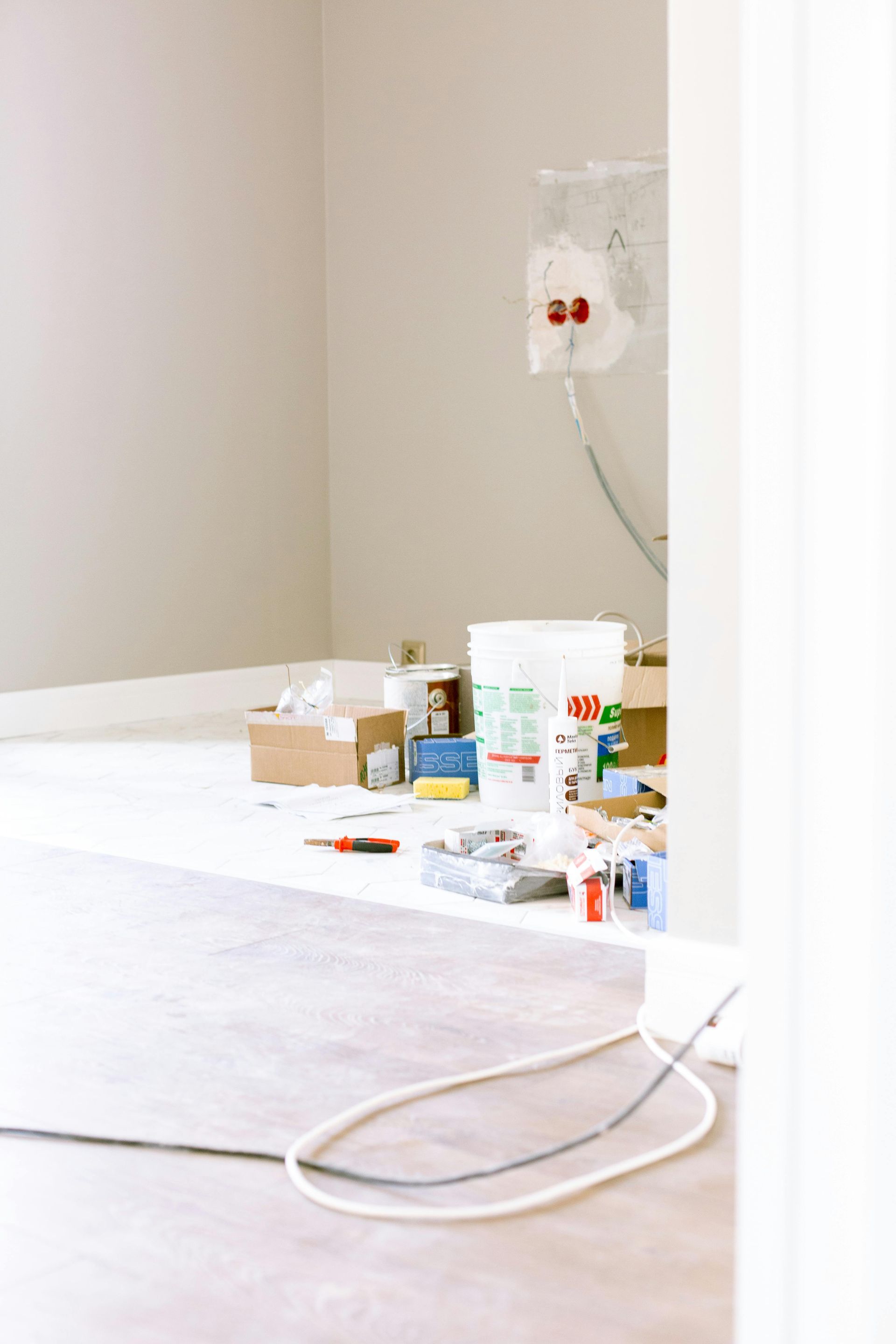 Room under construction, with tools, buckets, and exposed wiring on the floor.