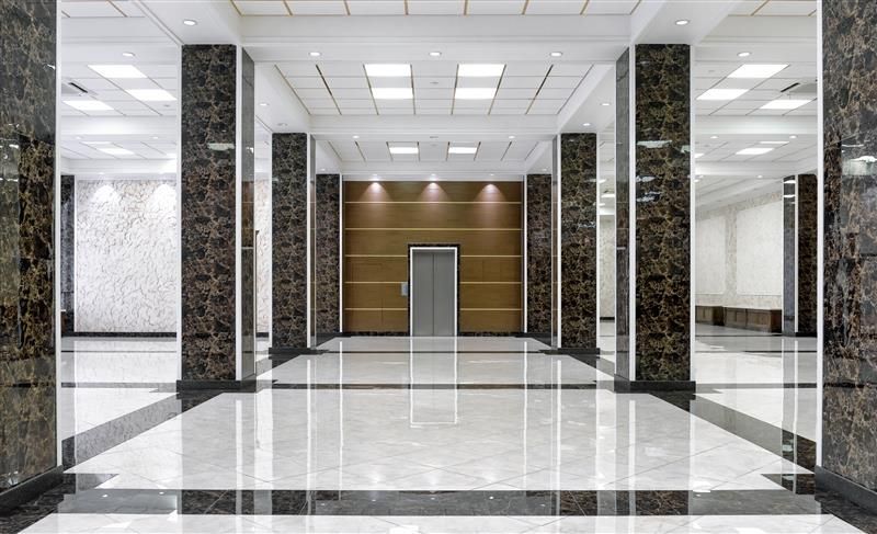 Hallway with marble floor and columns, elevator in background.