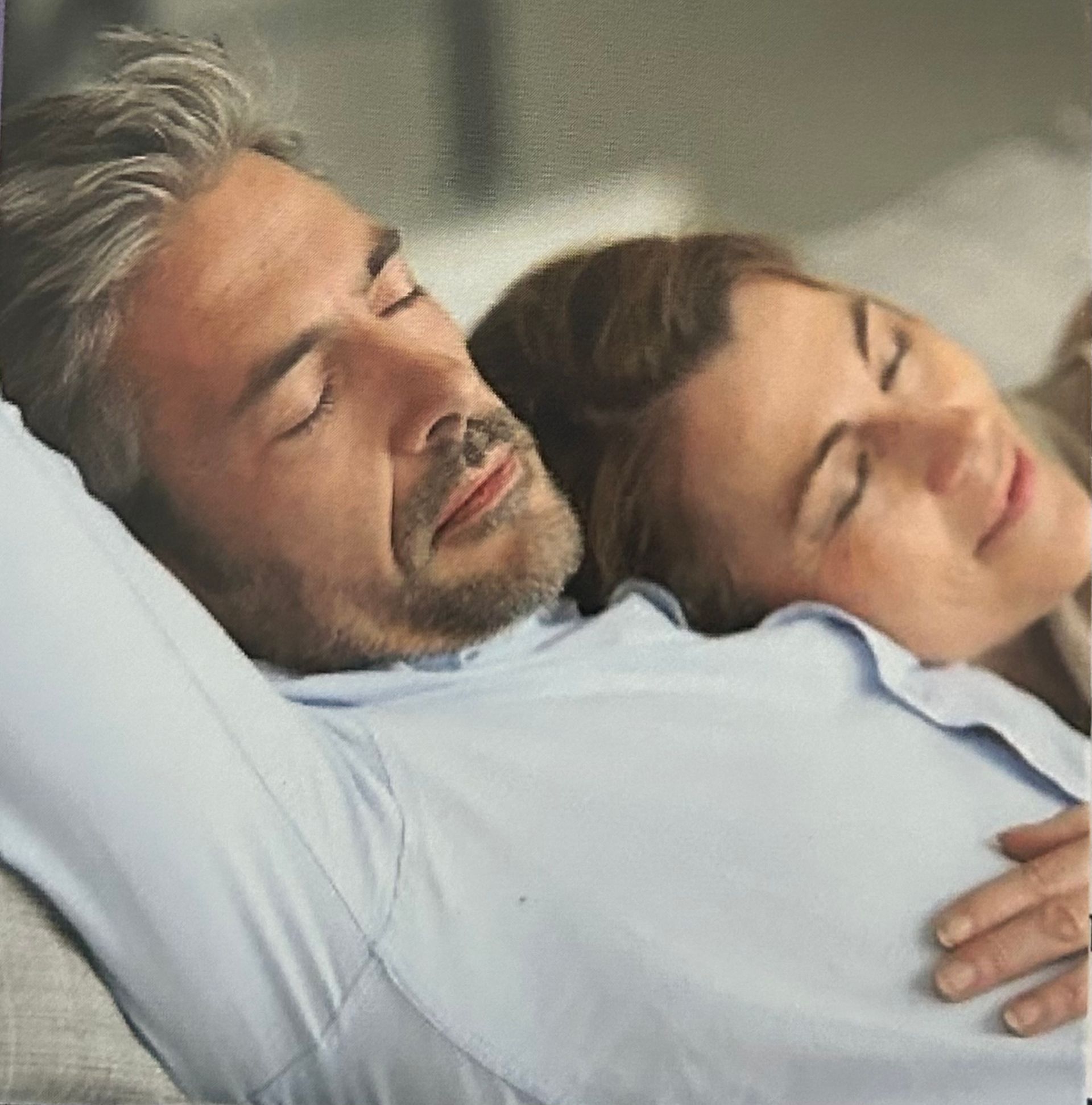 Man and woman asleep on a couch, heads close together.