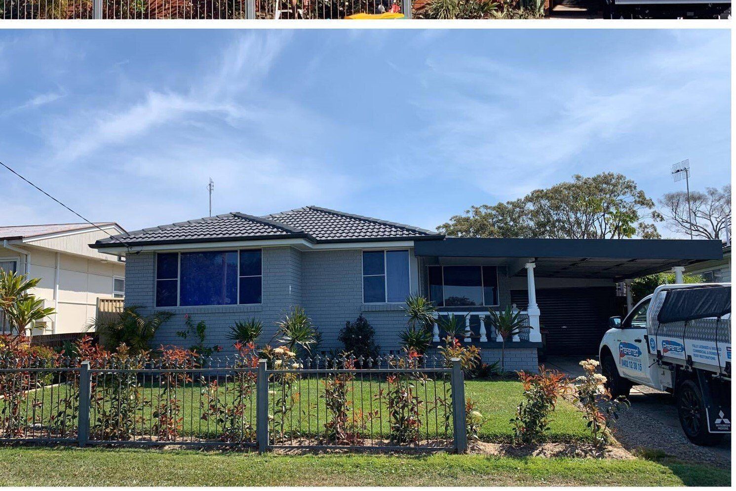 Gray house with carport, blue windows, and a white truck parked on a driveway.
