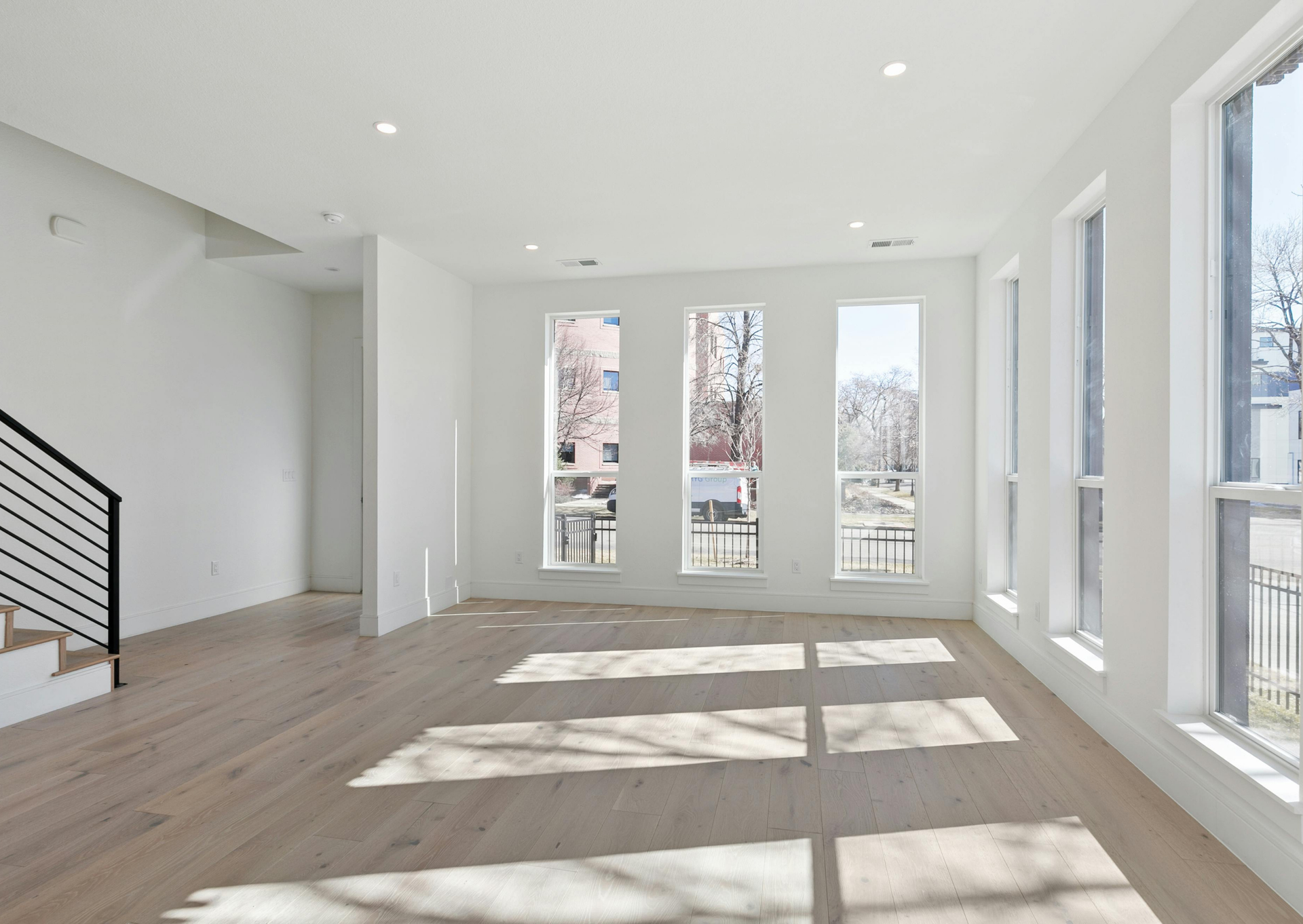 An empty living room with hardwood floors and lots of windows