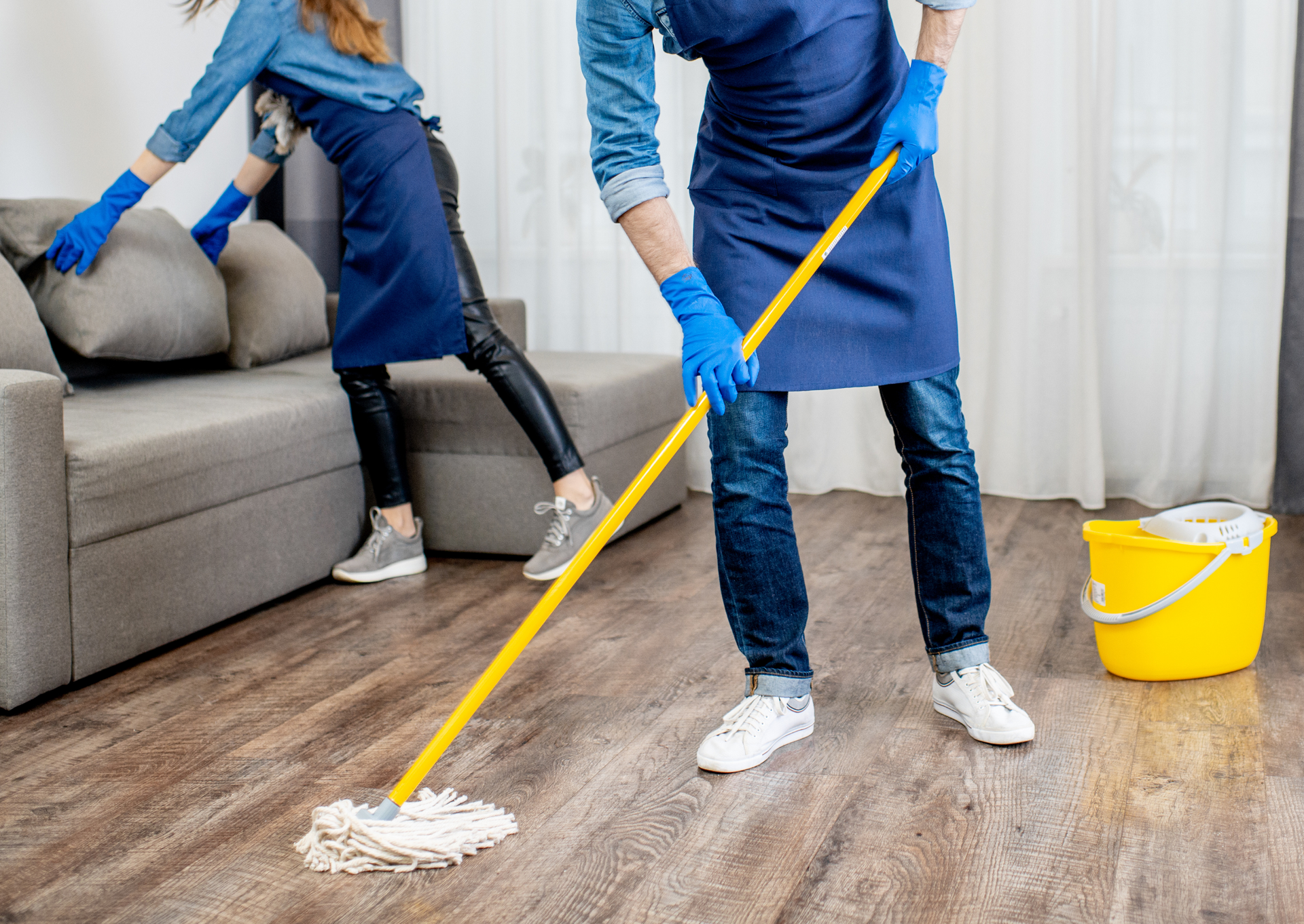 A man and a woman are cleaning the floor in a living room.