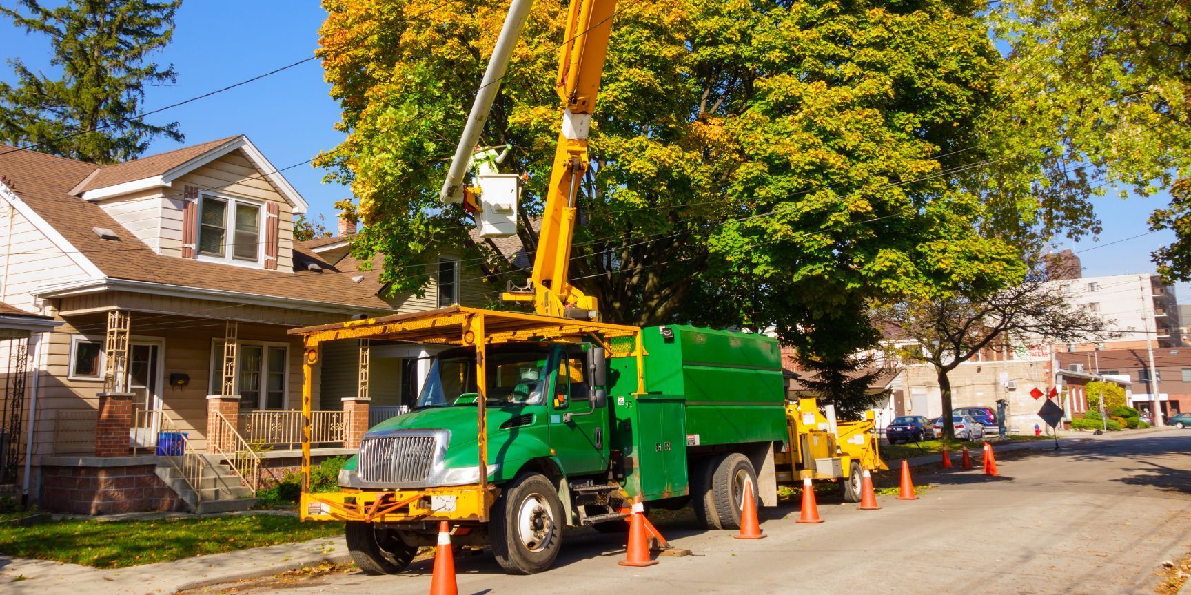 A green truck is parked on the side of the road in front of a house.