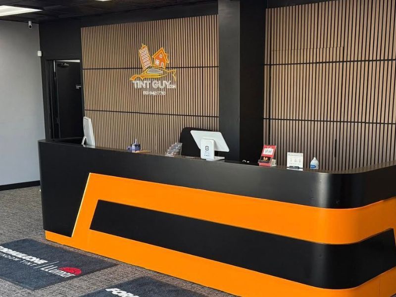 Reception desk at Tint Guy with the company logo behind it and where people will get window tint or PPF.
