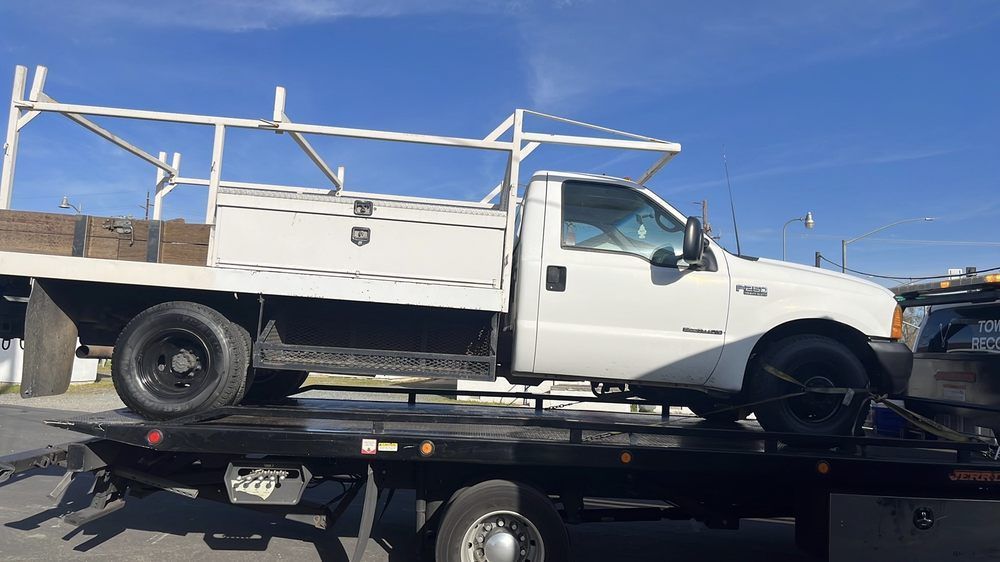 White flee truck with rack and toolbox on a tow truck.