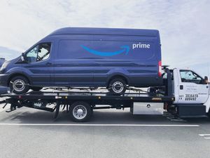 A fleet delivery van being on a flatbed truck.