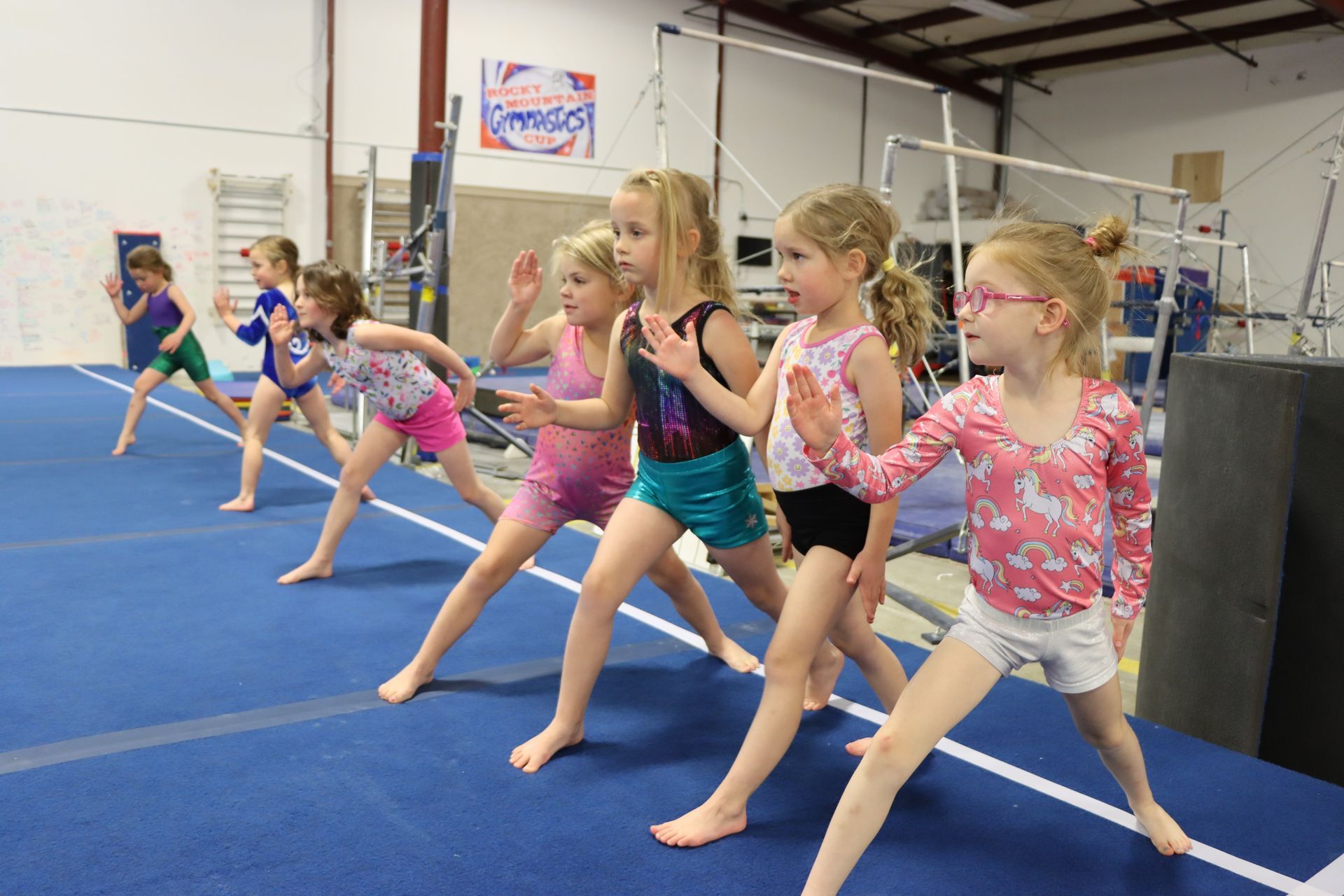 A young girl is standing on a balance beam in a gym.